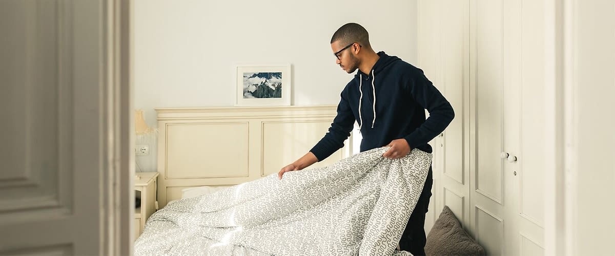 uomo cambia le lenzuola del letto