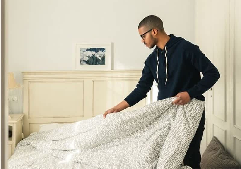 uomo cambia le lenzuola del letto