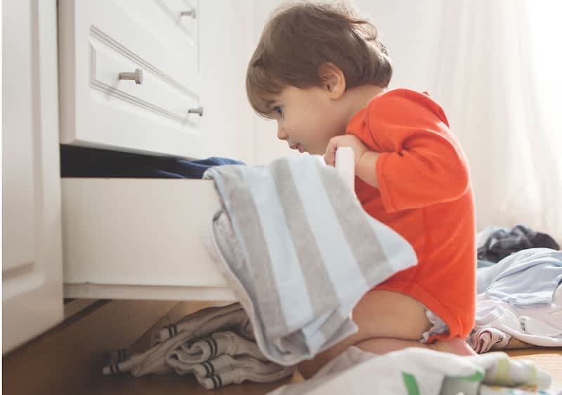 bambino cerca vestiti nell'armadio
