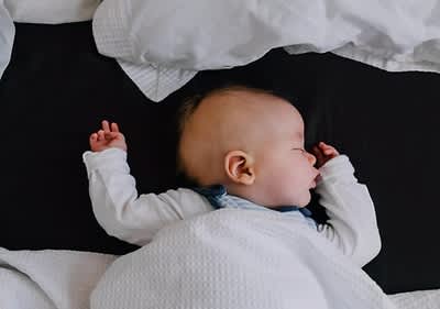 bebè dorme ben coperto sul letto