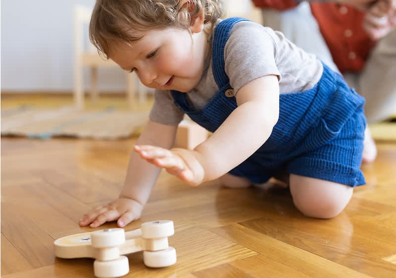 Bambino che gioca con un giocattolo su pavimento di legno