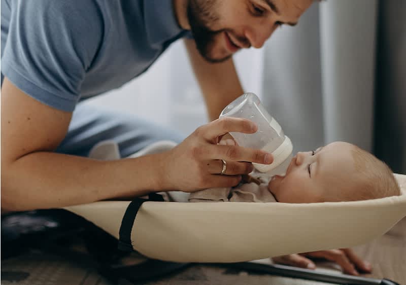 Papà che nutre il bambino con biberon in culla