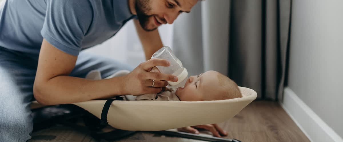Papà che nutre il bambino con biberon in culla