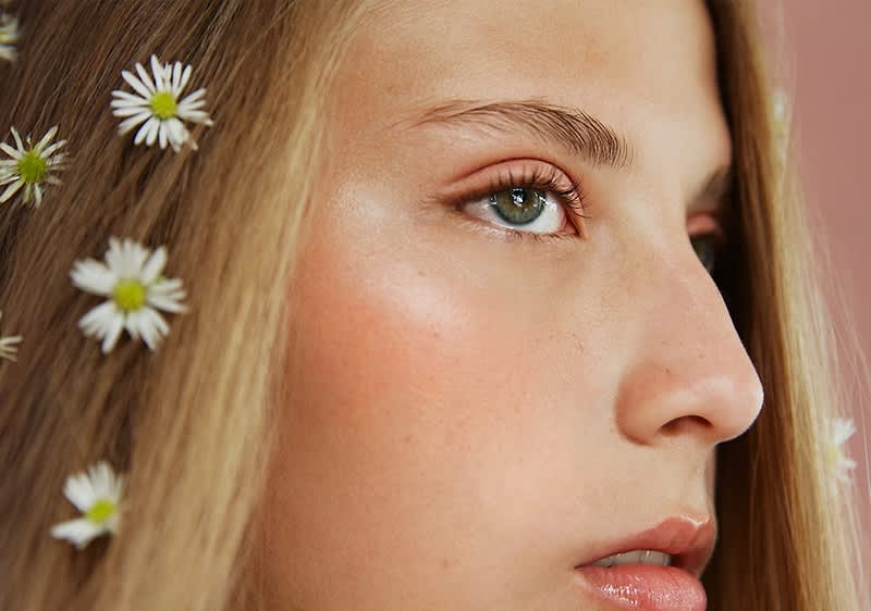 Ragazza con occhi verdi e capelli con fiori bianchi su sfondo sfocato