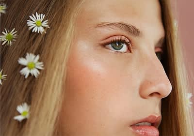 Ragazza con occhi verdi e capelli con fiori bianchi su sfondo sfocato