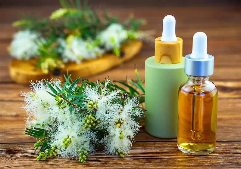 Olio essenziale di tea tree con fiori su tavolo di legno