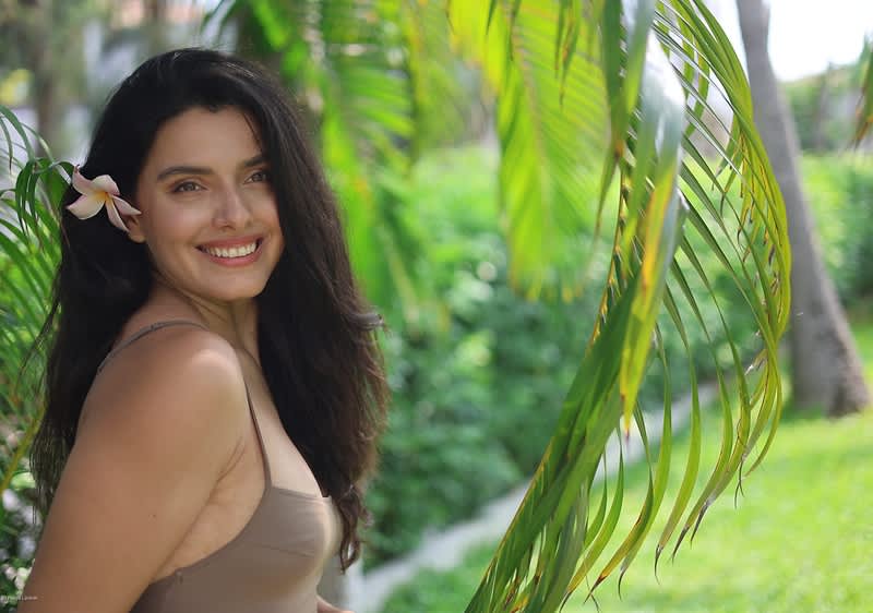 Donna con fiore tra i capelli sotto palme verdi