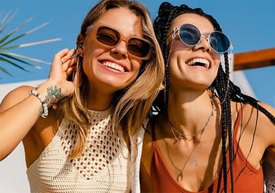 Due donne con abiti estivi e accessori alla moda ridono