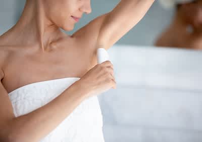 Donna applica deodorante sotto l'ascella