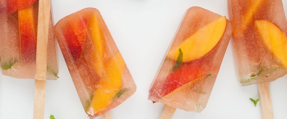 Ghiaccioli al tè e alla pesca con fette di frutta e menta