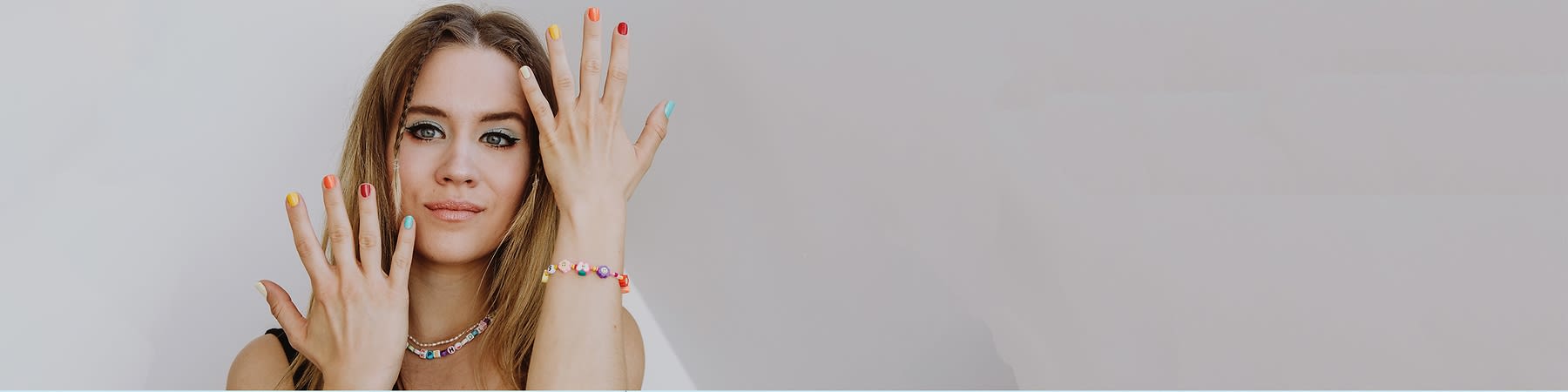 Ragazza con make-up occhi, unghie colorate e braccialetto di perline