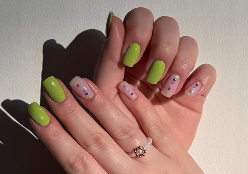 Unghie con smalto verde e decorazioni colorate