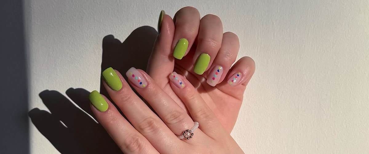 Unghie con smalto verde e decorazioni colorate