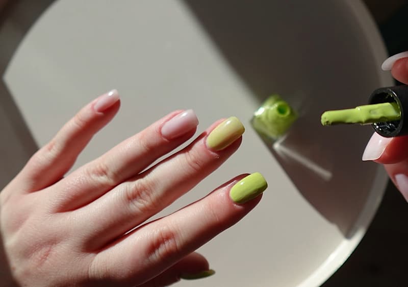 Applicazione smalto verde su unghie