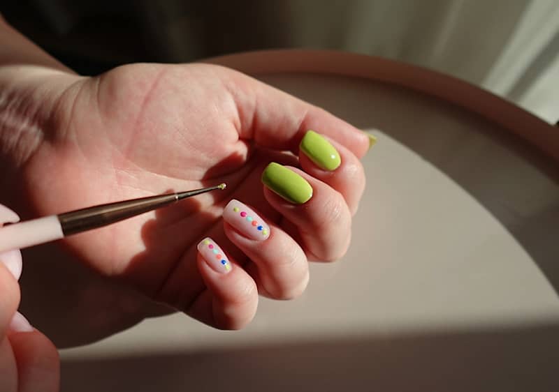 Manicure con smalto verde e decorazioni colorate su unghie