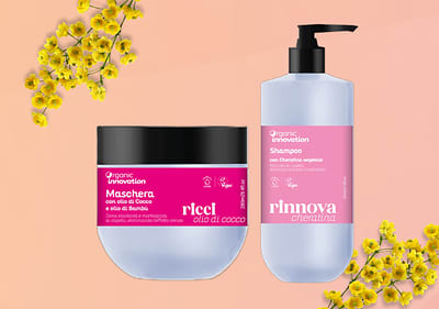 Prodotti per capelli Organic Innovation con olio di cocco e cheratina su sfondo rosa con fiori gialli