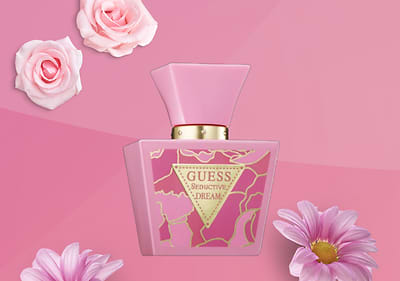 Flacone profumo GUESS Seductive Dream su sfondo rosa con fiori rosa