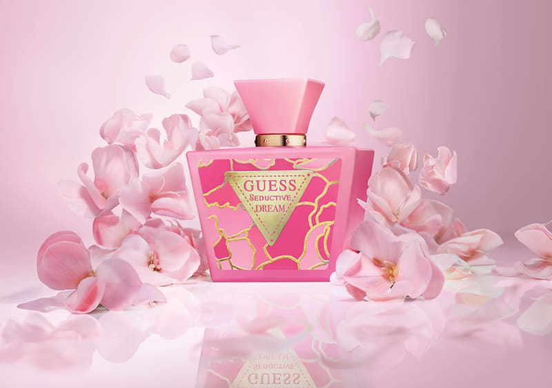 Bottiglia di profumo Guess Seductive Dream circondata da petali rosa