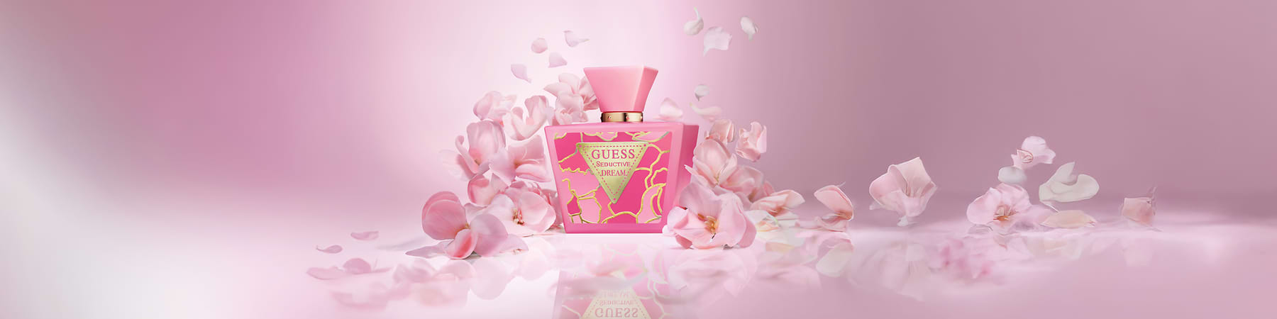 Bottiglia di profumo Guess Seductive Dream circondata da petali rosa