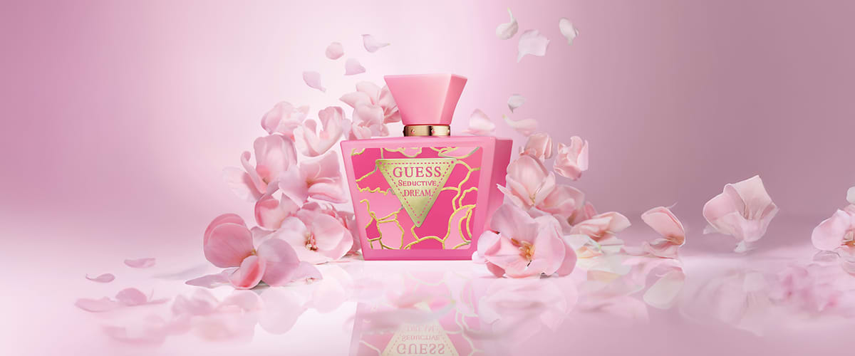 Bottiglia di profumo Guess Seductive Dream circondata da petali rosa