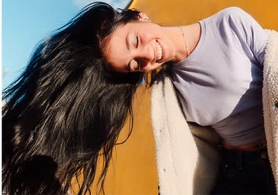 Ragazza con capelli lunghi neri al vento con sfondo giallo