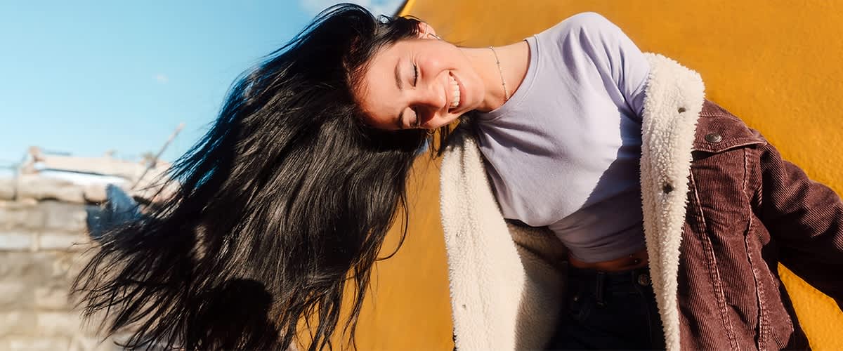 Ragazza con capelli lunghi neri al vento con sfondo giallo