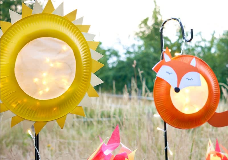 Decorazioni fatte con piatti di carta a forma di sole e volpe in un giardino