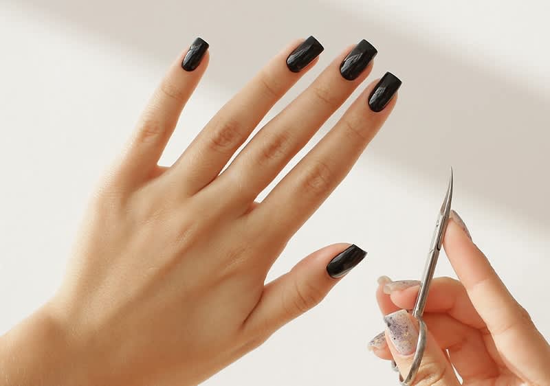 Manicure con unghie nere e forbici per unghie