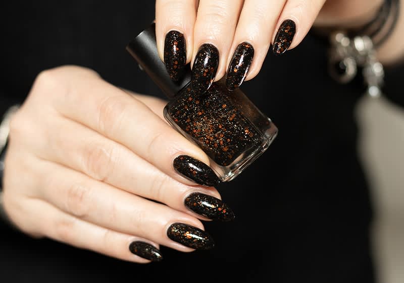 Smalto nero glitterato su unghie lunghe e affusolate