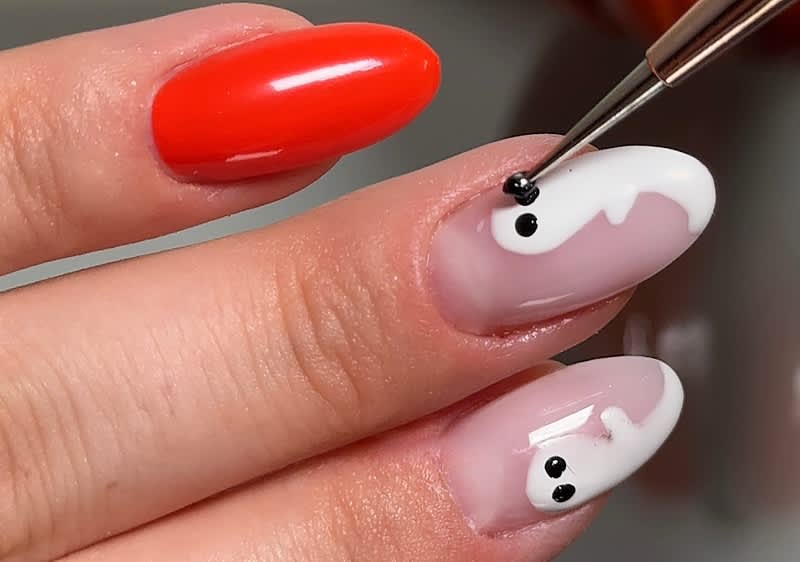 Nail art con fantasmi su unghie arancioni e bianche