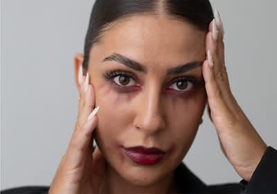 Ragazza con capelli scuri con trucco da vampiro e manicure con unghie appuntite bianche