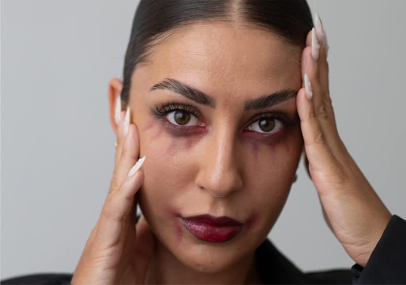 Ragazza con capelli scuri con trucco da vampiro e manicure con unghie appuntite bianche