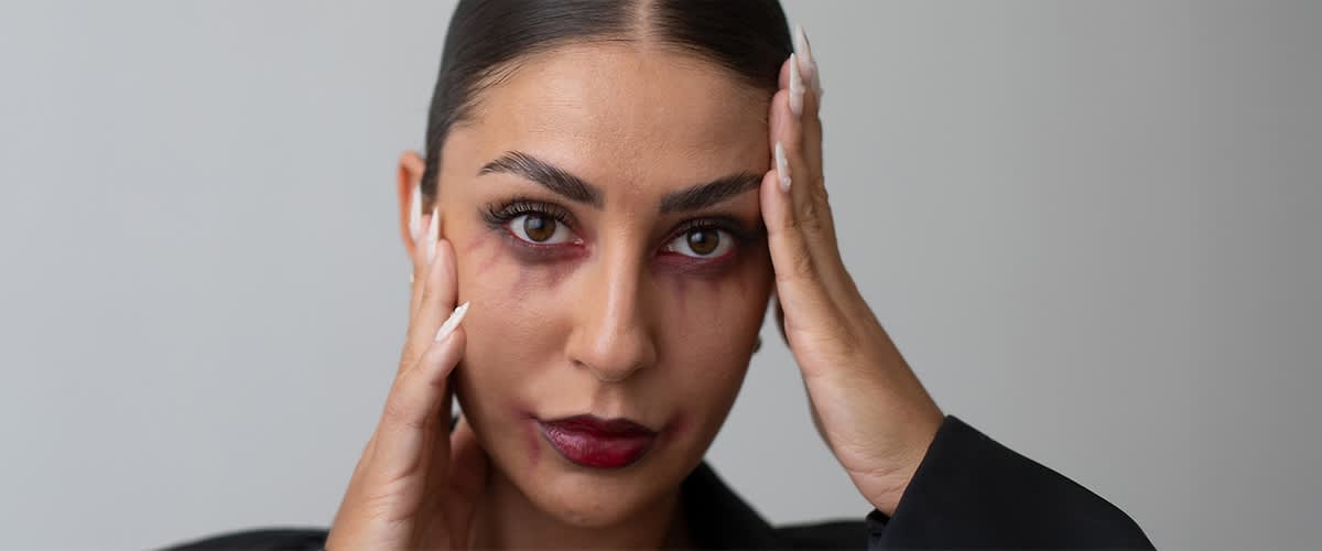 Ragazza con capelli scuri con trucco da vampiro e manicure con unghie appuntite bianche