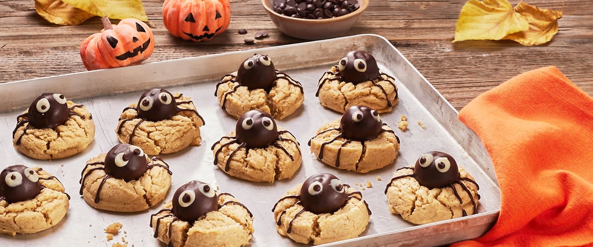 Biscotti ragno di Halloween su teglia con zucche decorative sullo sfondo