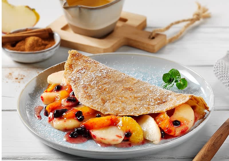 Crepes vegane ripiene con frutta e salsa su piatto grigio