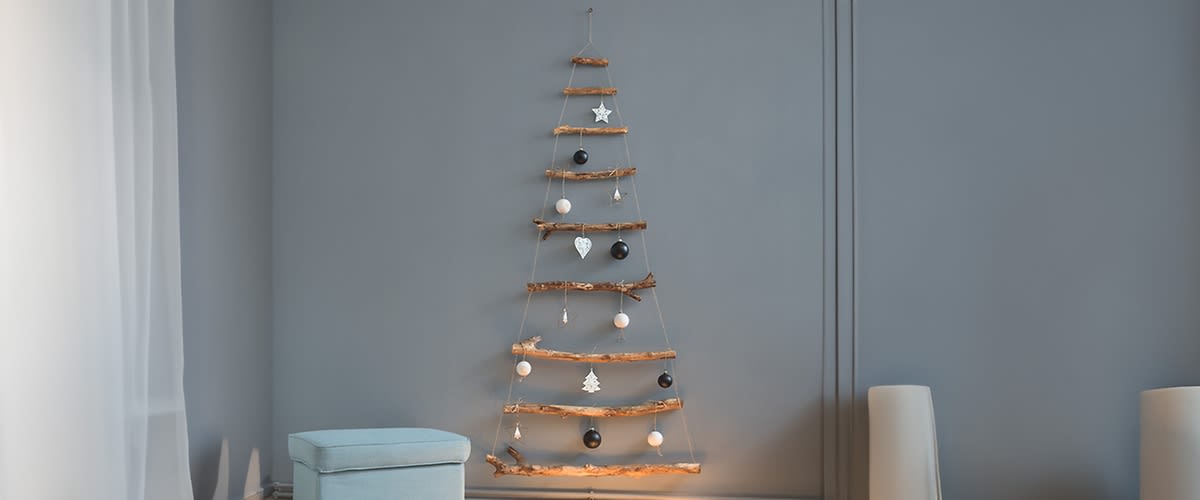 Albero di Natale alternativo minimalista con rami e decorazioni su parete grigia