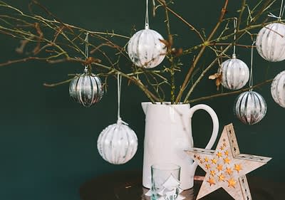 Albero di Natale alternativo con rametti di legno in un vaso addobbato con palline di Natale
