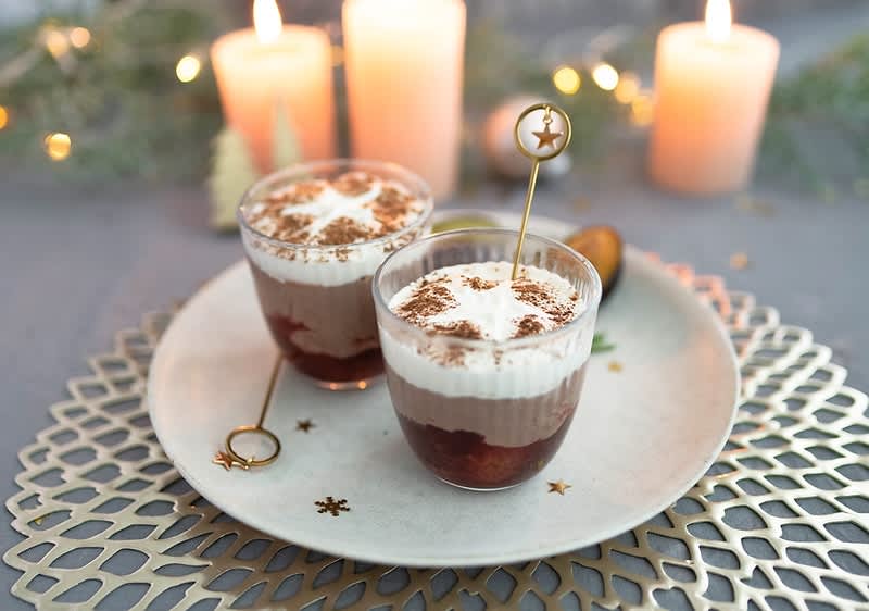 Dessert di Natale con panna su piatto decorato e candele sullo sfondo
