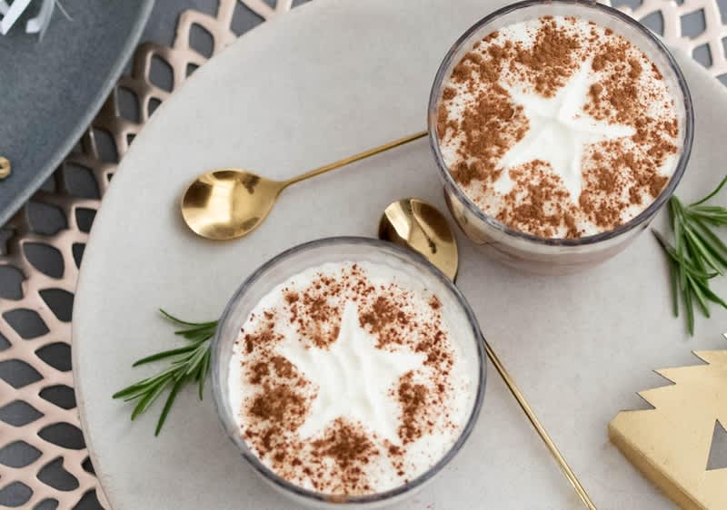Dessert nel bicchiere con panna e cannella decorato con stelle su tavolo con cucchiaini dorati