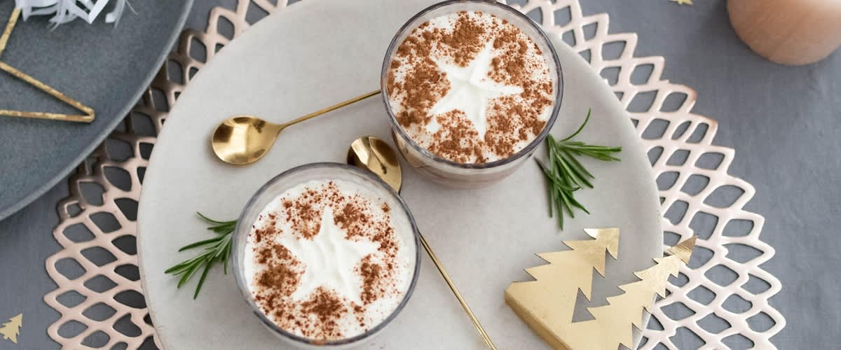 Dessert nel bicchiere con panna e cannella decorato con stelle su tavolo con cucchiaini dorati