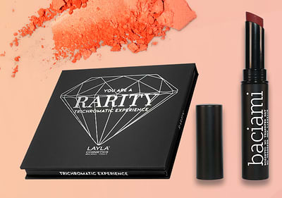 Trucco con palette e rossetto Layla su sfondo arancione con ombretto in polvere