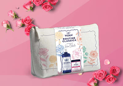 Trousse con prodotti per la cura della pelle a marchio Acqua alle rose su sfondo rosa con rose