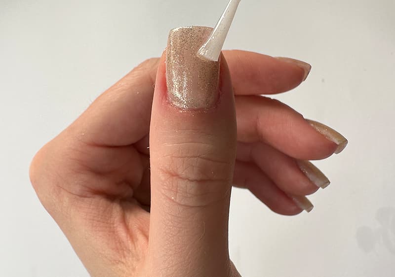 Applicazione di smalto top coat su manicure con smalto glitterato