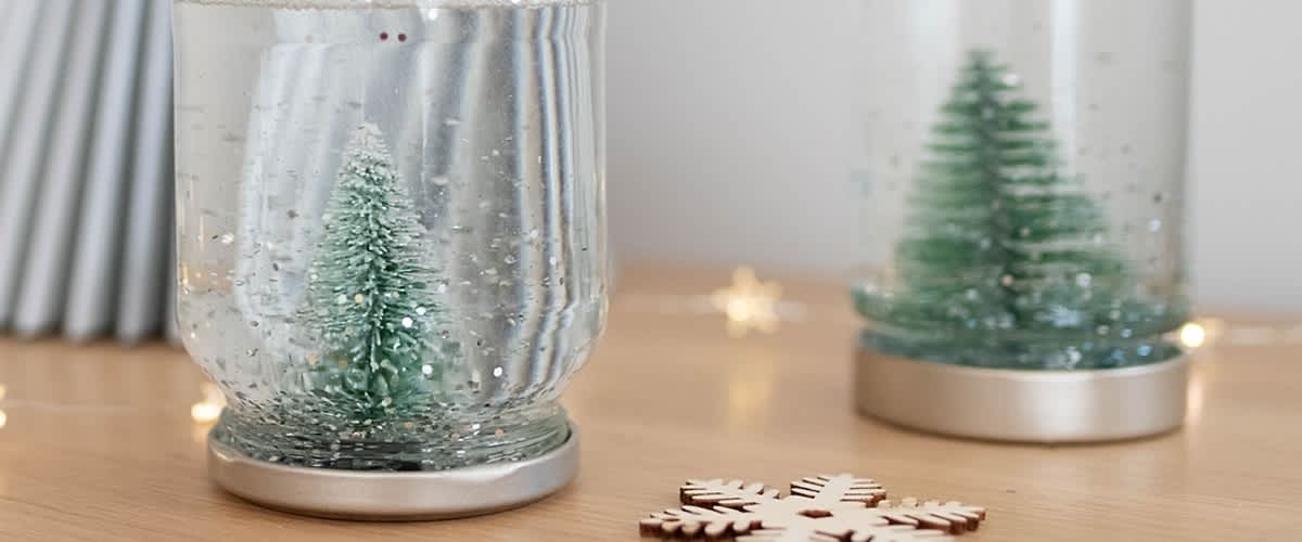 Albero di Natale in una palla di vetro con neve finta su tavolo di legno