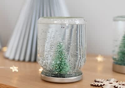 Palla di neve con albero di Natale su tavolo decorato