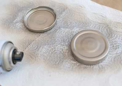 Coperchi di metallo verniciati con spray su carta assorbente