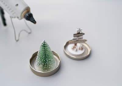 Decorazioni natalizie con albero dentro il coperchio di un barattolo e pistola per colla