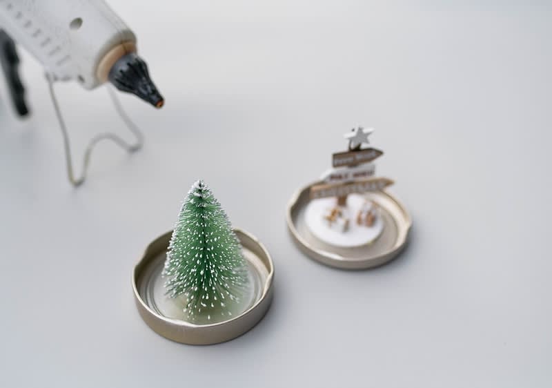 Decorazioni natalizie con albero dentro il coperchio di un barattolo e pistola per colla