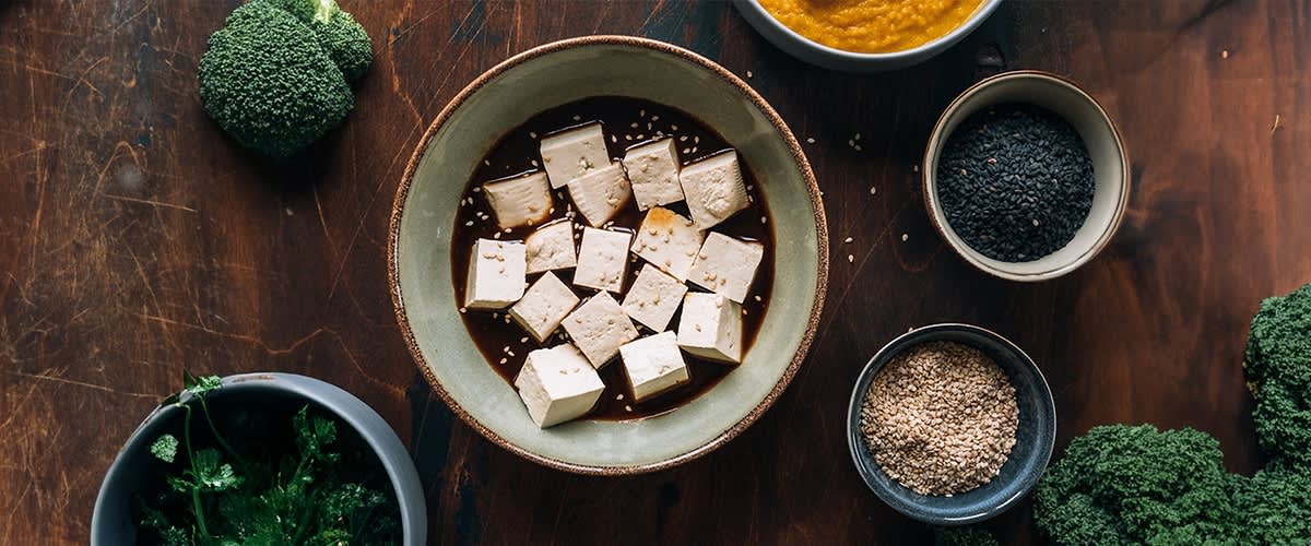 Ciotola di tofu con salsa e semi su tavolo di legno