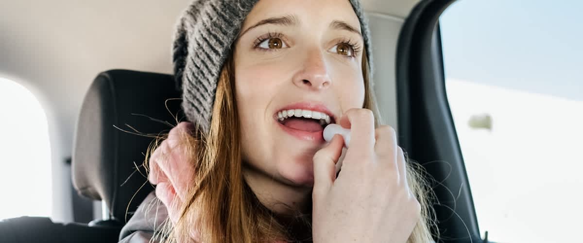 Donna giovane con abbigliamento invernale si applica burrocacao sulle labbra mentre è in macchina